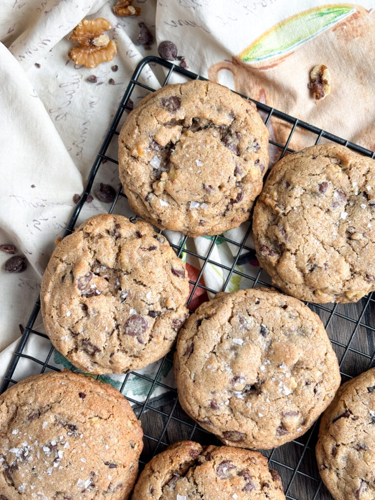 large chocolate chip cookies on a cooling rack on top of a cloth apron.